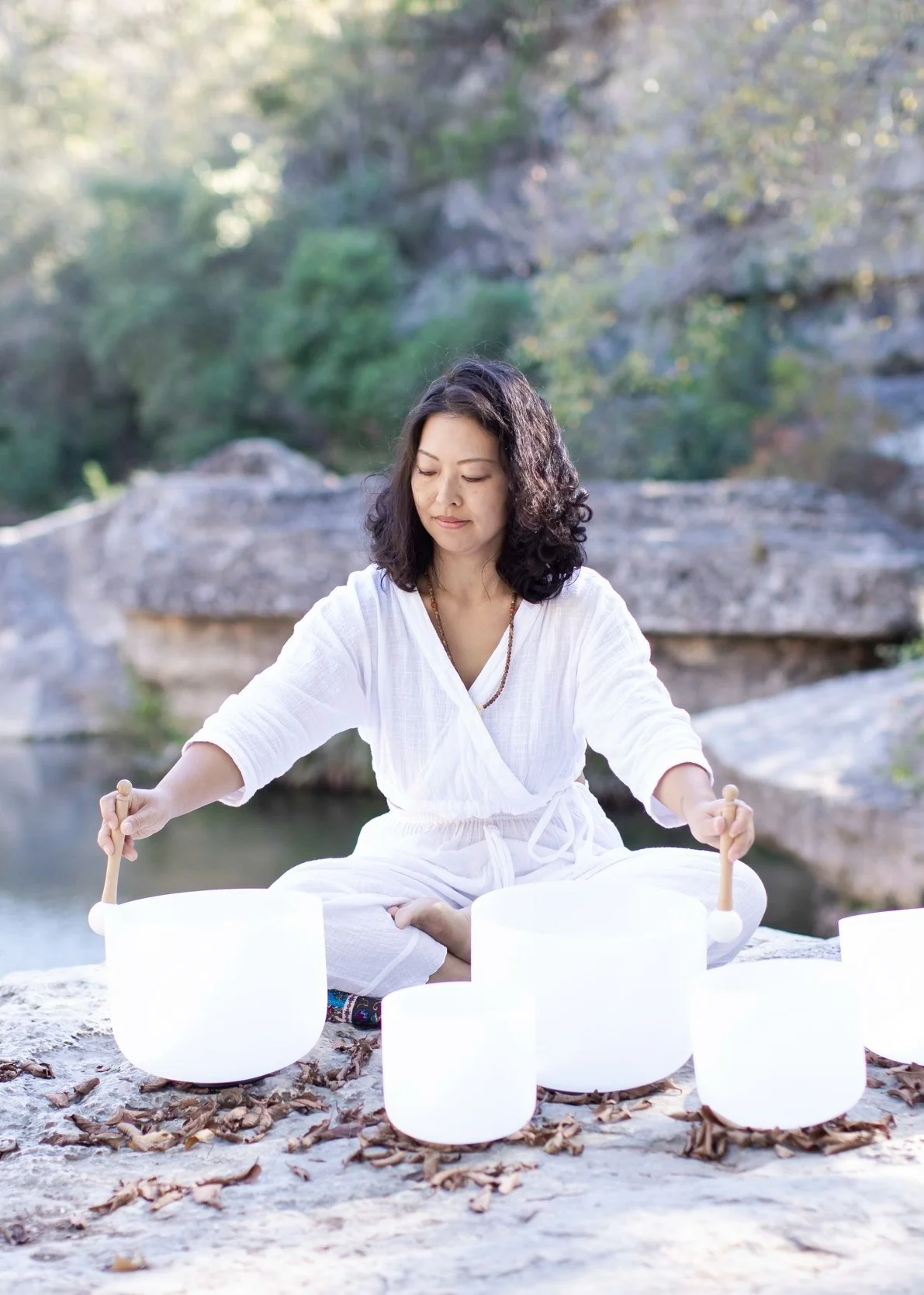 Yolanda playing five crystal singing bowls on a limestone creek bank in Austin
